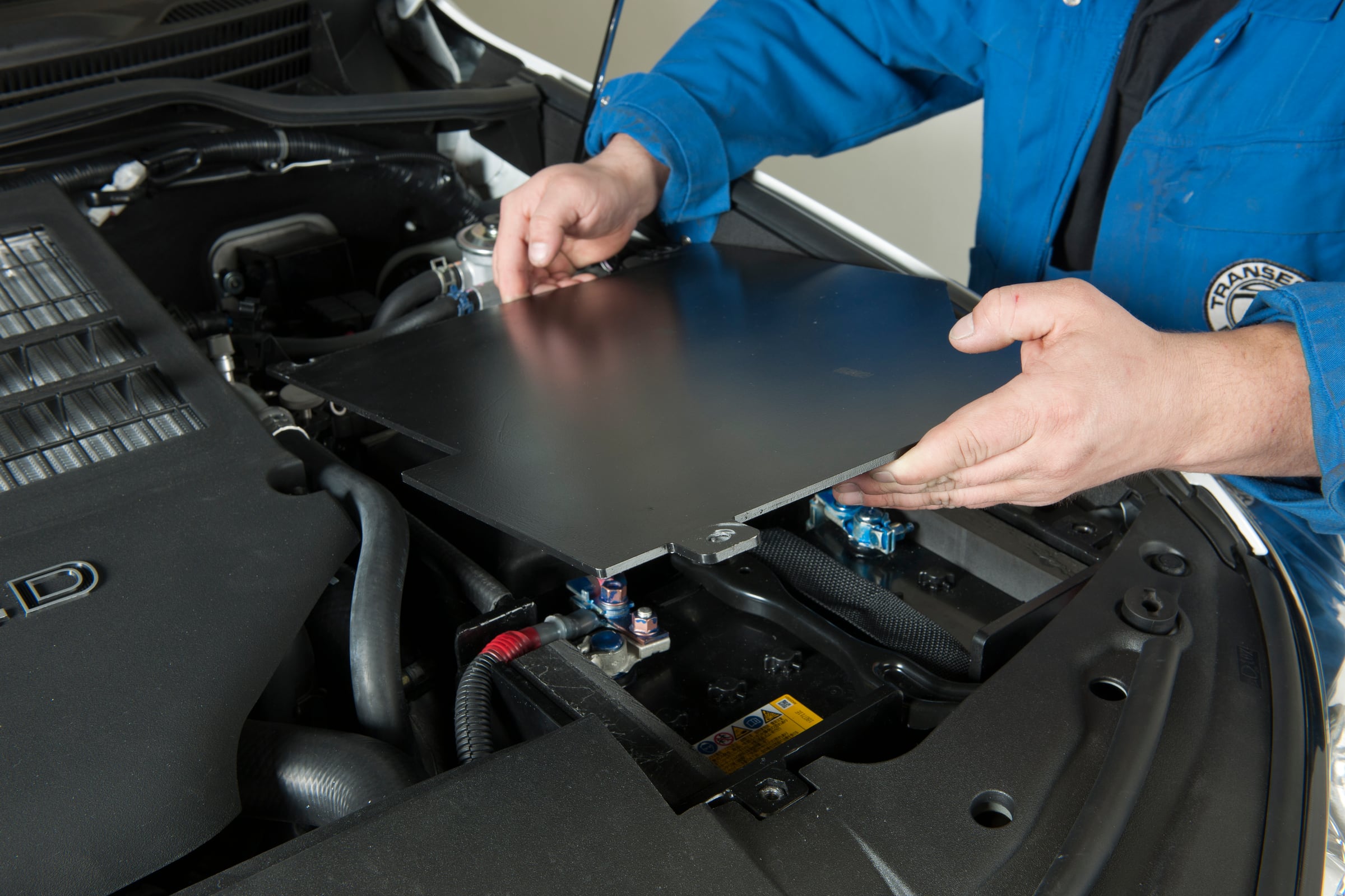 Armor plate being fitted over the battery in the engine bay of an armored Toyota Land Cruiser