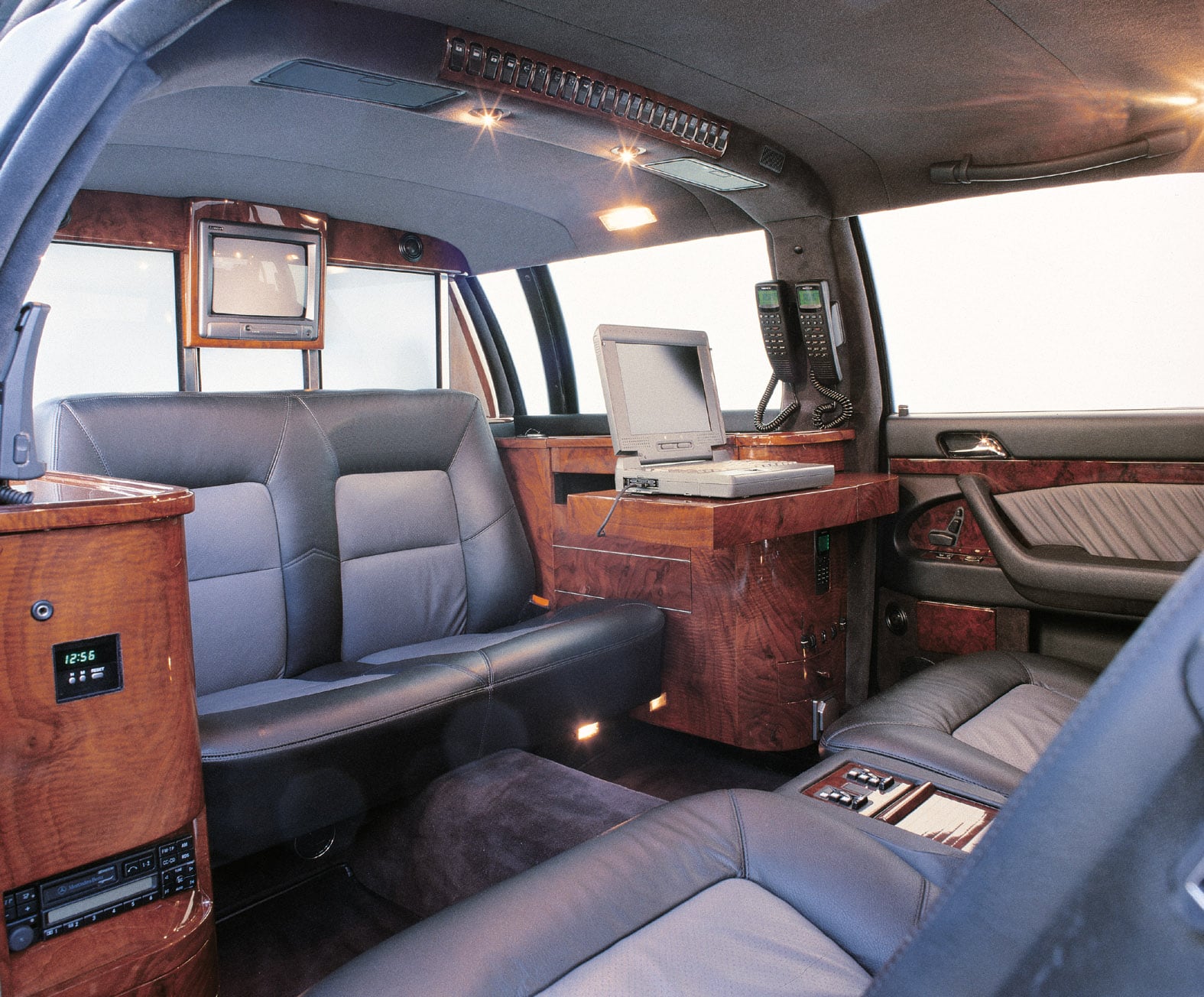 Rear compartment of an extended limousine with partition wall, monitor and wood veneer console