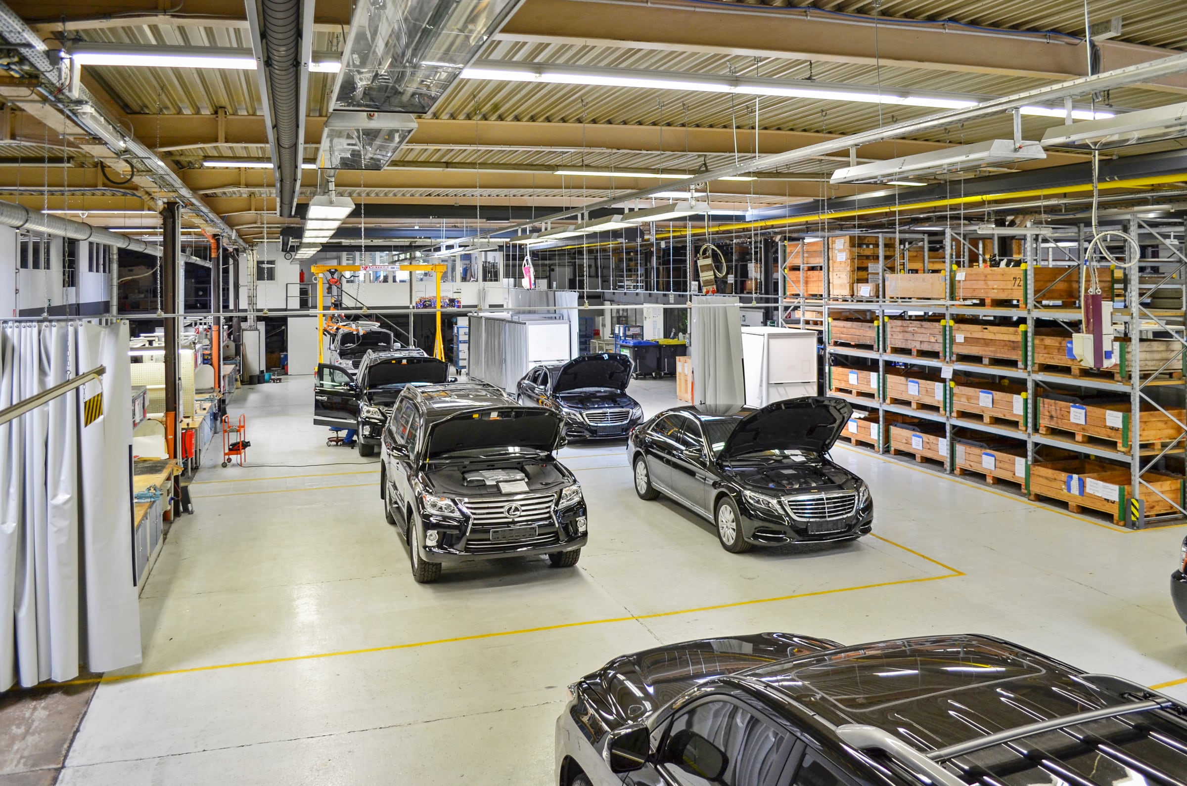 SUV et berlines blindés dans le hall de production de TRASCO, avec le magasin de pièces